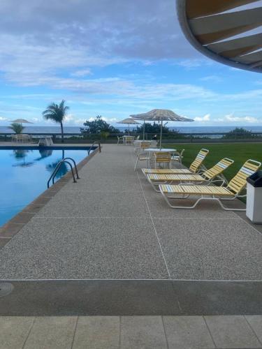 a group of chairs and an umbrella next to a pool at Auromar in Caraballeda