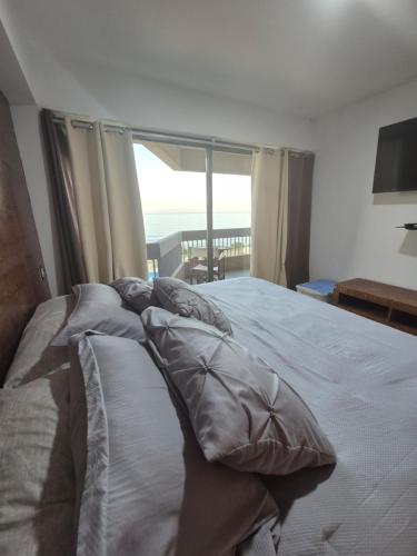 a bedroom with a bed with pillows and a window at Auromar in Caraballeda