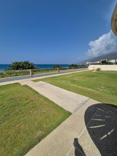 a walkway next to a field of grass with the ocean at Auromar in Caraballeda