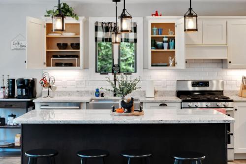 a kitchen with white cabinets and a island with bar stools at Mitten Pines Cabin Hot Tub Fire Pit in Conway