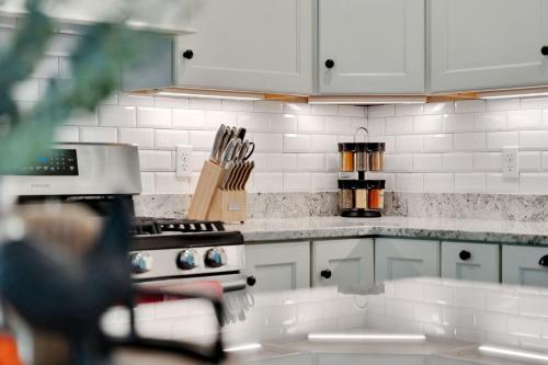 a kitchen with white cabinets and a stove at Mitten Pines Cabin Hot Tub Fire Pit in Conway
