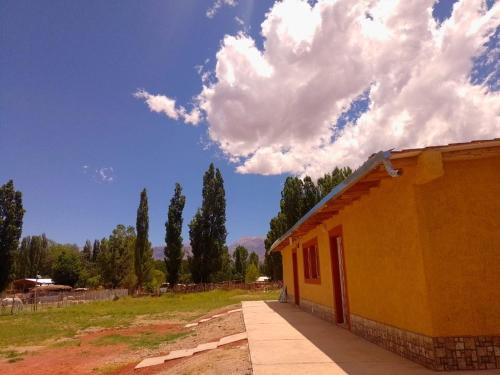 a yellow building with a blue sky and clouds at Casas de montañas in Uspallata