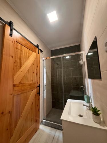a bathroom with a shower and a sink and a wooden door at Casa de Campos AL in Angra do Heroísmo