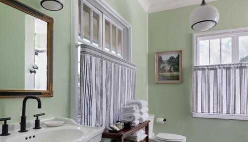 a bathroom with a sink and a mirror and a window at The Historic Wailuku Inn Maui in Wailuku