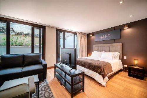 a bedroom with a bed and a chair and a television at Morph Candelaria - Gestion Hotelera in Bogotá