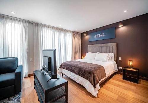a hotel room with a bed and a television at Morph Candelaria - Gestion Hotelera in Bogotá