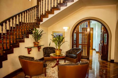 a living room with a staircase with chairs and a table at Best Western Plus Hotel Stofella in Guatemala