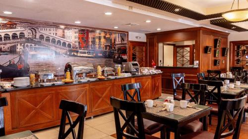 a restaurant with tables and chairs and a bar at Best Western Plus Hotel Stofella in Guatemala