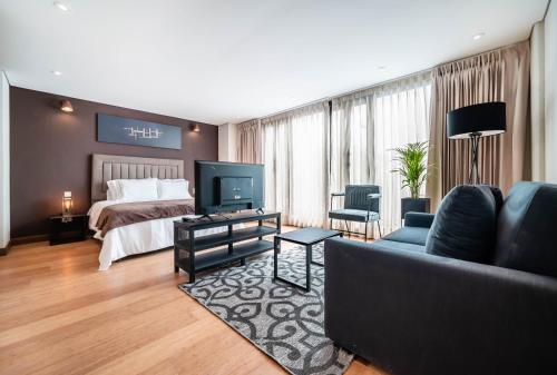 a hotel room with a bed and a couch and a television at Morph Candelaria - Gestion Hotelera in Bogotá