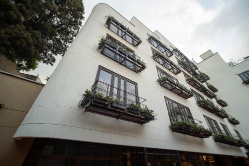 a white building with windows and potted plants on it at Morph Candelaria - Gestion Hotelera in Bogotá