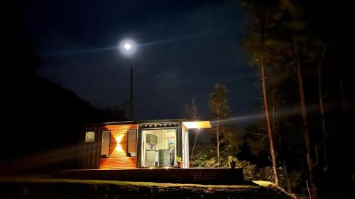 a tiny house at night with the moon in the background at Pousada Motta in Miguel Pereira