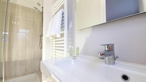 une salle de bain blanche avec un lavabo et une douche dans l'établissement Tour du Guet 1, à Calais