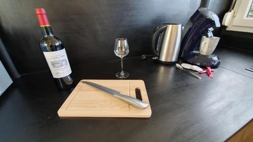 un couteau sur une planche de découpe à côté d'une bouteille de vin dans l'établissement Tour du Guet 2, à Calais