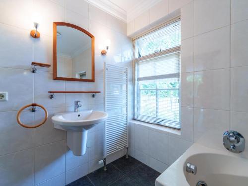 a white bathroom with a sink and a mirror at de Spil in Winterswijk-Meddo