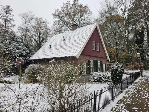 a red house with a white roof in the snow at de Spil in Winterswijk-Meddo