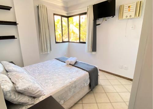 a bedroom with a bed and a television in it at Apartamento recantoazul es Conforto Total a 50m do Mar Apartamento Recém-Reformado na Praia de Castelhanos, ES, para 7 Pessoas Aconchegante e Completo, com 3 Quartos e 1 Suíte in Anchieta