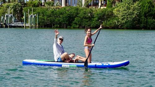 a man and a girl on a paddle board on the water at Private Patio, Walk to All, 2min- Siesta Keys Best Beach, 1min- Dining & Entertainment of Village! in Siesta Key