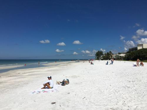 a person sitting on a towel on a beach at Private Patio, Walk to All, 2min- Siesta Keys Best Beach, 1min- Dining & Entertainment of Village! in Siesta Key