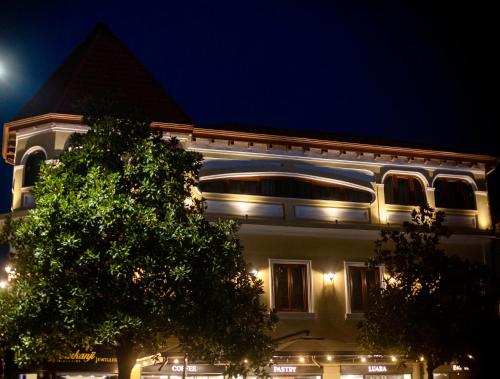 un edificio de noche con un árbol delante en Hotel Vila 101-New Bazaar, en Tirana
