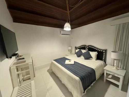 a bedroom with a bed and a flat screen tv at Pousada Coisa e Tao in Arraial d'Ajuda