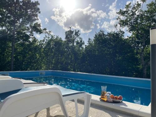 a pool with white chairs and a table and a drink at Holiday house with a swimming pool Grubine, Zagora - 22263 in Krivodol
