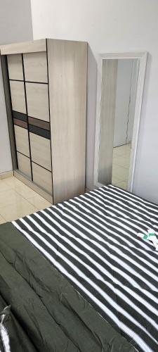 a bedroom with a bed with a black and white stripes at CozyRizqy Homestay at Kebun Baru - 3R2B in Jenjarum
