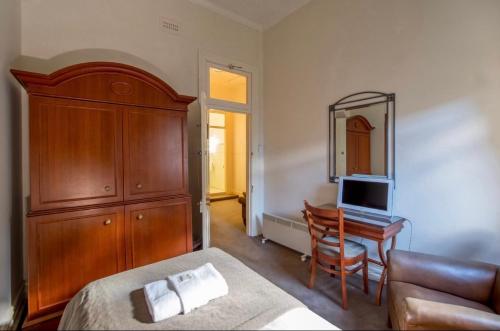 a bedroom with a bed and a dresser and a desk at American Hotel Creswick in Creswick