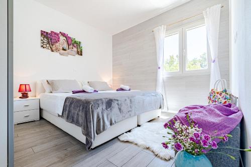 - une chambre blanche avec un lit et un vase de fleurs dans l'établissement Seaside family friendly house with a swimming pool Grscica, Korcula - 23487, à Blato
