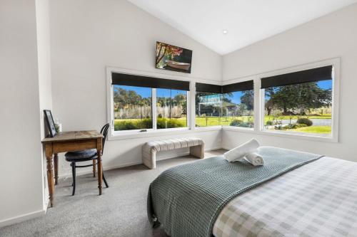 a bedroom with a bed and a desk and windows at Limestone Views in Swan Reach