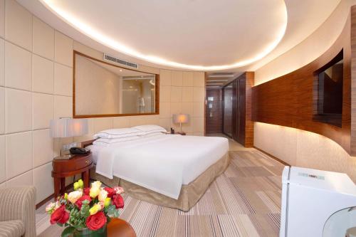 a bedroom with a bed and a table with flowers at Guangzhou Good International Hotel in Guangzhou