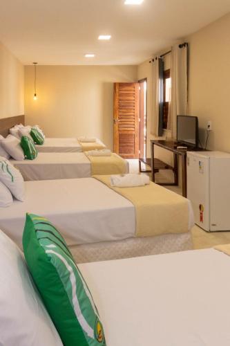 a hotel room with four beds and a television at Santa Areia Lençóis Pousada in Santo Amaro