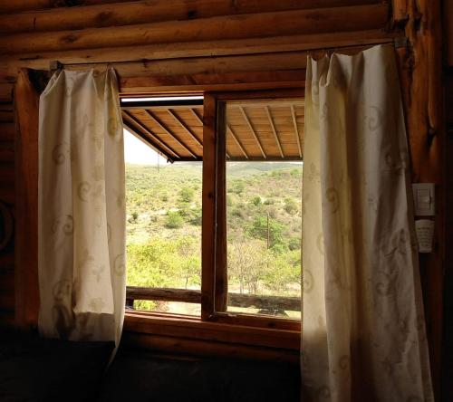 ein Fenster in einem Zimmer mit Blick auf ein Feld in der Unterkunft vistas del valle Cabaña in Valle Hermoso