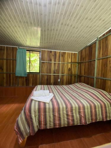 a bedroom with a bed in a room with wooden walls at Casitas de Montaña Cabuya in Monteverde Costa Rica