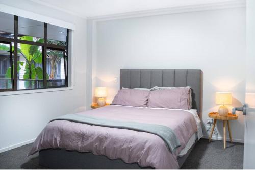 een slaapkamer met een bed met twee lampen en een raam bij The Downtown - A Mount Maunganui Apartment in Mount Maunganui