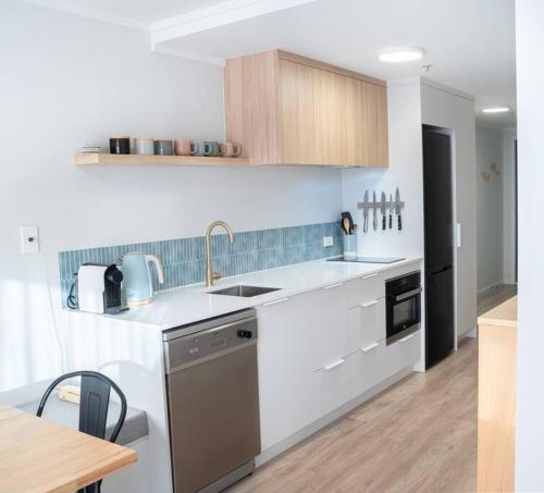 een keuken met een wastafel en een vaatwasser bij The Downtown - A Mount Maunganui Apartment in Mount Maunganui
