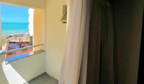 a room with a window with a view of the ocean at Hotel Atlântico in Guarapari