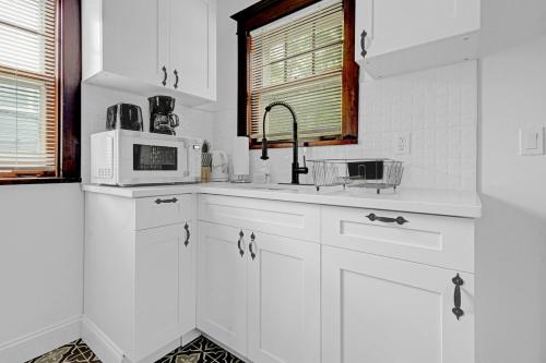 a white kitchen with a sink and a microwave at Spacious 4BR 1BA near the Falls in Niagara Falls