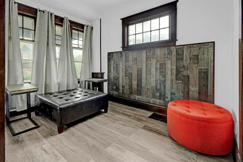 a living room with a red ottoman and a chair at Spacious 4BR 1BA near the Falls in Niagara Falls