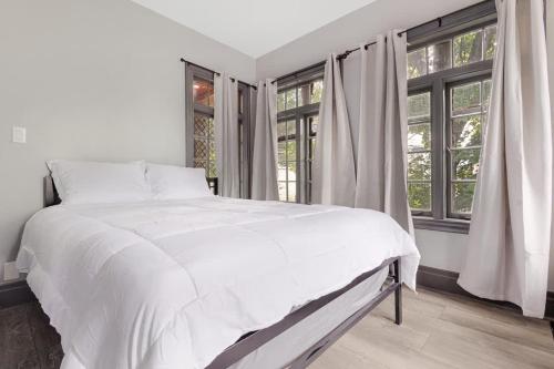 a white bed in a room with windows at Cozy 4BR 1BA close to the Falls in Niagara Falls
