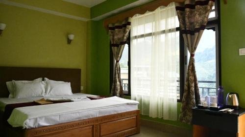 a bed in a green bedroom with a window at Mantra Inn Lachung in Lachung