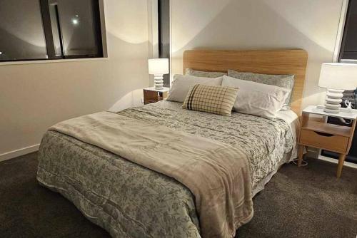 a bedroom with a bed with two lamps and two tables at 2-bedroom ensuite, close to city, comfortable, accessible with own parking in Christchurch