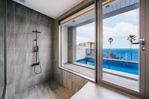 a bathroom with a window and a view of the ocean at Ddosi Aewol Pool Villa in Jeju