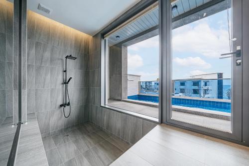 a bathroom with a shower and a large window at Ddosi Aewol Pool Villa in Jeju