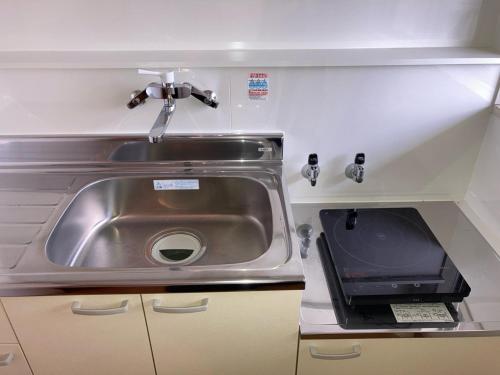 a kitchen sink with a microwave next to it at 長野善光寺ビラ大門402号室 in Nagano