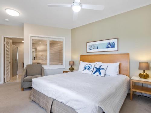 a bedroom with a large bed and a chair at The Pool Resort Kingscliff - Private Apartments by Holiday Management Company in Kingscliff