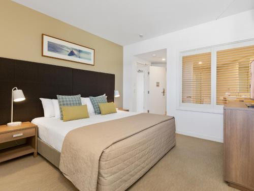 a bedroom with a large bed and a window at The Pool Resort Kingscliff - Private Apartments by Holiday Management Company in Kingscliff