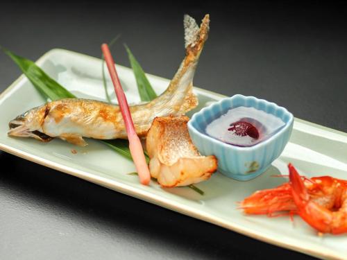 a plate of food with shrimp and a bowl of dipping sauce at Arai Ryokan in Izu