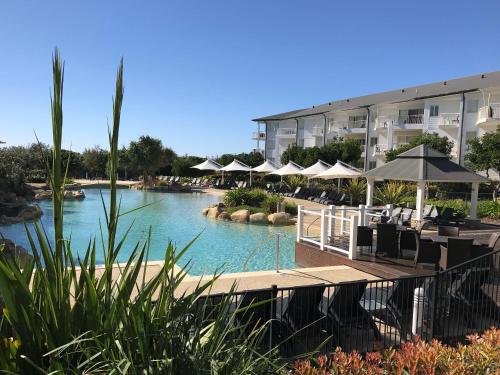 a pool with tables and umbrellas in a hotel at The Pool Resort Kingscliff - Private Apartments by Holiday Management Company in Kingscliff