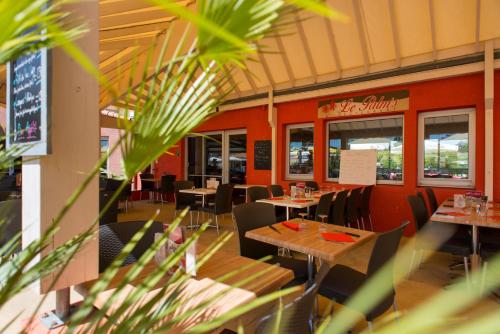 a dining room with tables and chairs in a restaurant at Camping Officiel Siblu Les Charmettes in Les Mathes