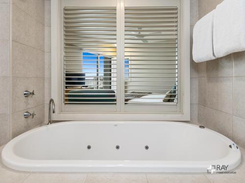 a bath tub in a bathroom with a window at The Pool Resort Kingscliff - Private Apartments by Holiday Management Company in Kingscliff